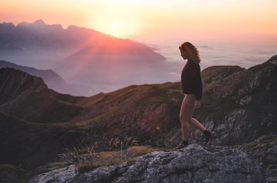 Randonneuse au sommet d'une montagne au lever du soleil, au-dessus d'une mer de nuages